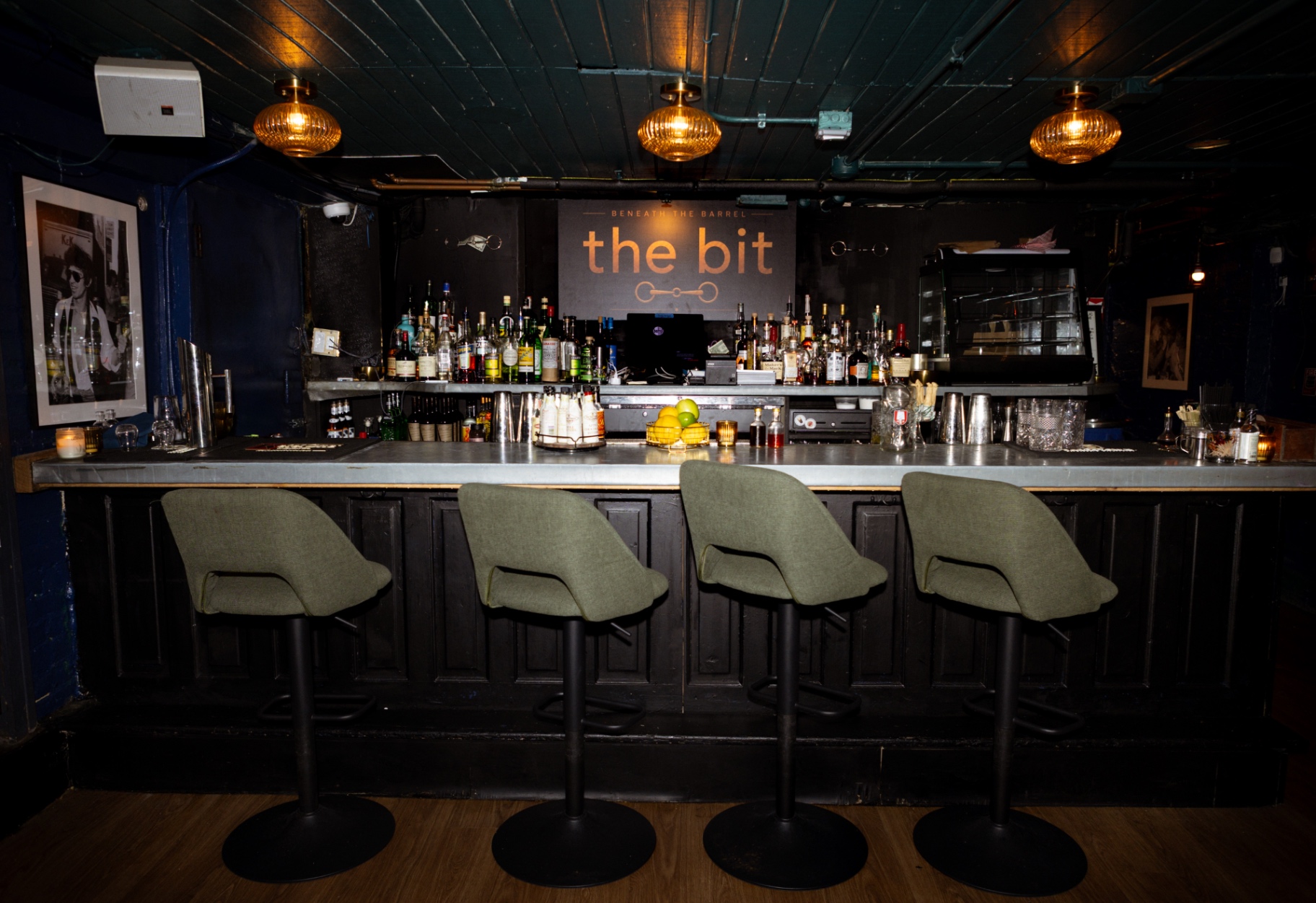 The bar at the bit with four green stools beneath warm pendant lights